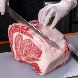 butcher cutting into block of wagyu steak